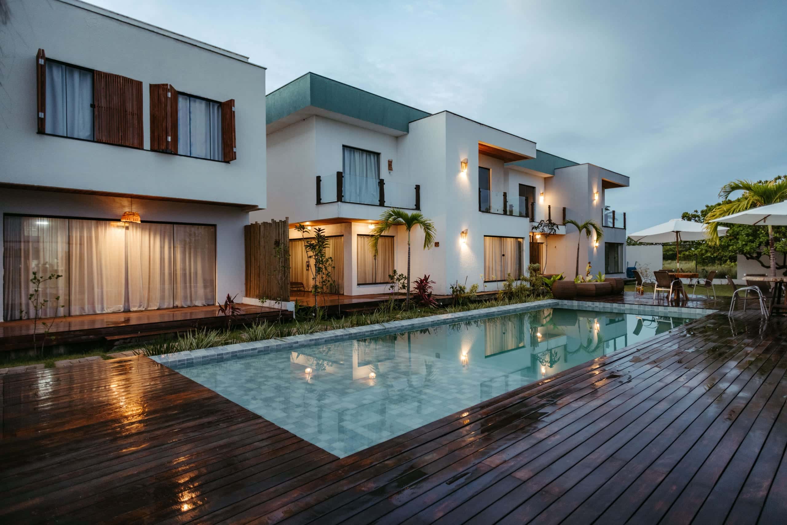 Backyard pool at dusk with warm villa lights reflecting in calm turquoise water